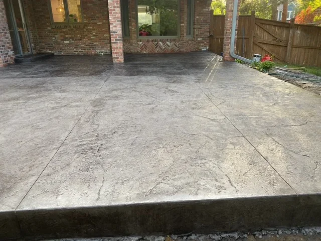 Stamped concrete patio with slate texture pattern and control joints at brick home