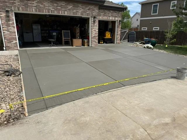 Newly poured concrete driveway with control joints and brick garage facade