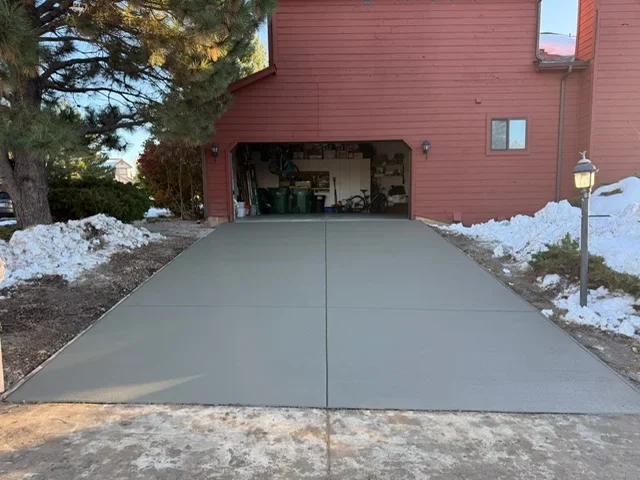 Gray concrete driveway with control joints leading to red brick garage