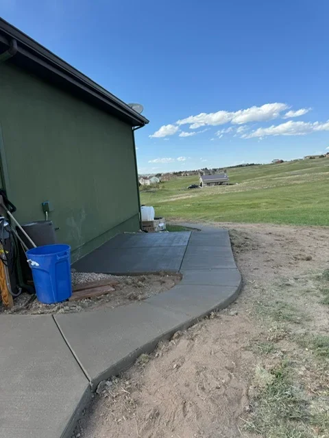 Finished concrete pad next to rural home with gravel base and clear drainage slope
