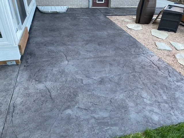 Gray stamped concrete patio with slate texture pattern adjacent to home