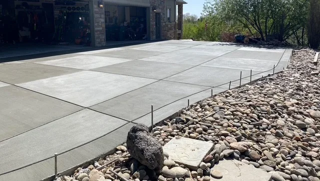 Large concrete patio with control joints and river rock border edging