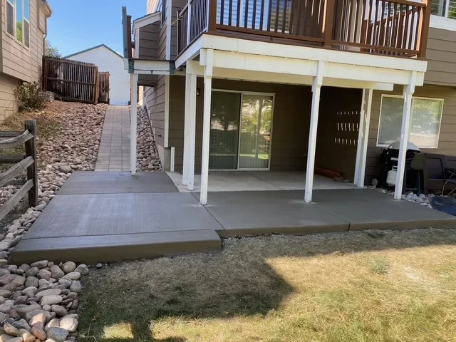 Stamped concrete patio with white posts and multi-level walkway in residential backyard