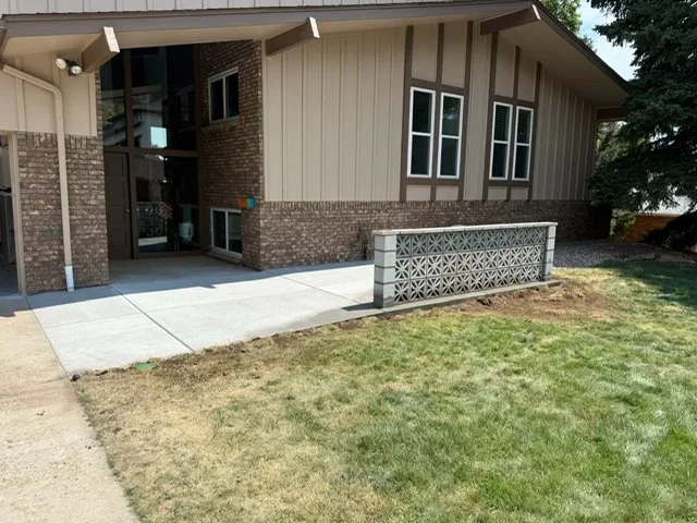 Finished concrete patio and walkway with decorative planter box at residential home