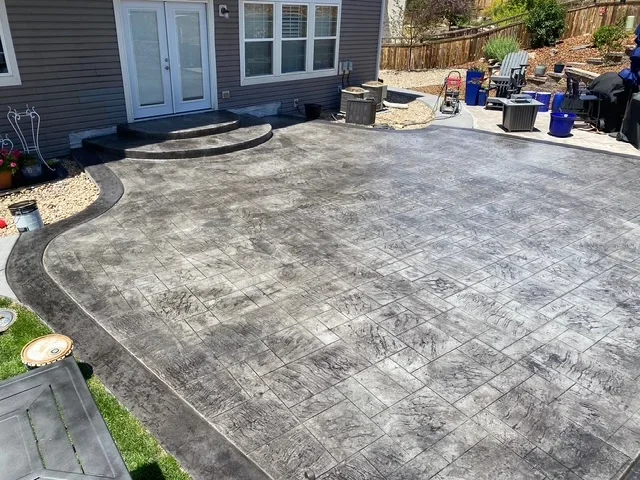 Gray stamped concrete patio with curved borders and slate texture pattern