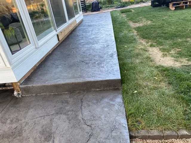 Finished concrete patio and walkway next to home with green lawn
