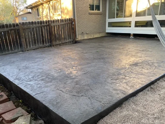 Stamped concrete patio with slate texture and dark border edging in residential backyard