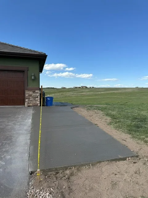 New concrete driveway next to garage with rural landscape backdrop